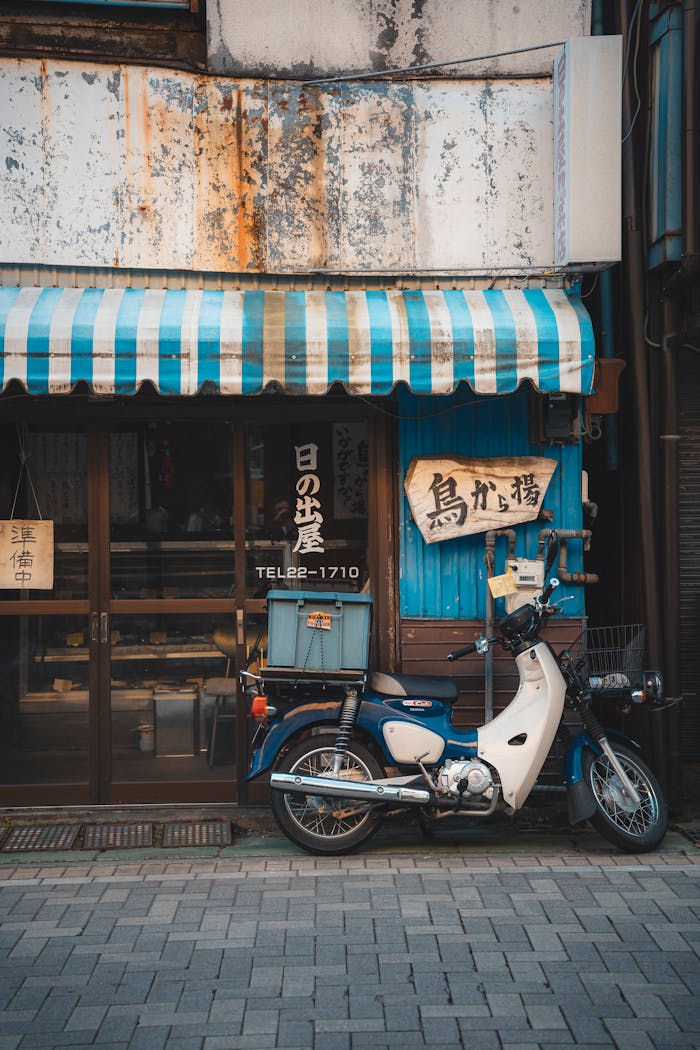 Vintage scooter parked outside a rustic Japanese shop in an urban street.