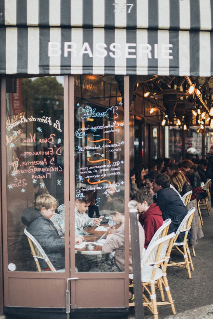 Lively brasserie scene with people enjoying outdoor dining in an urban setting.
